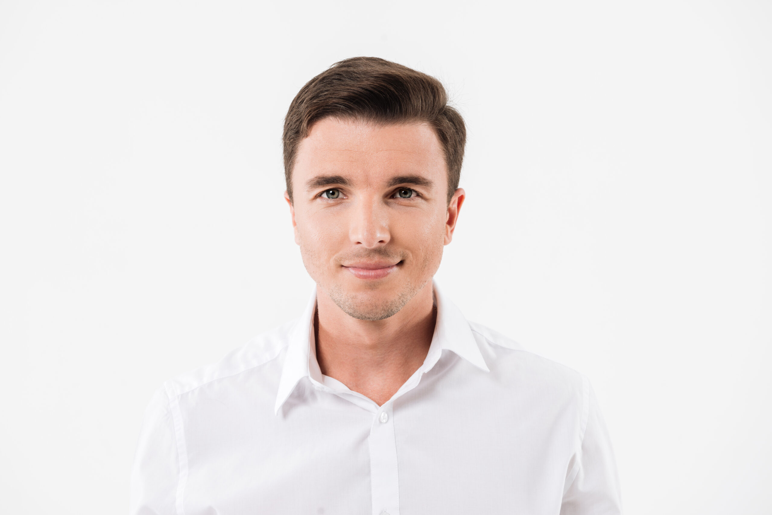 Close up portrait of a young smiling man in a white shirt looking at camera isolated over white background